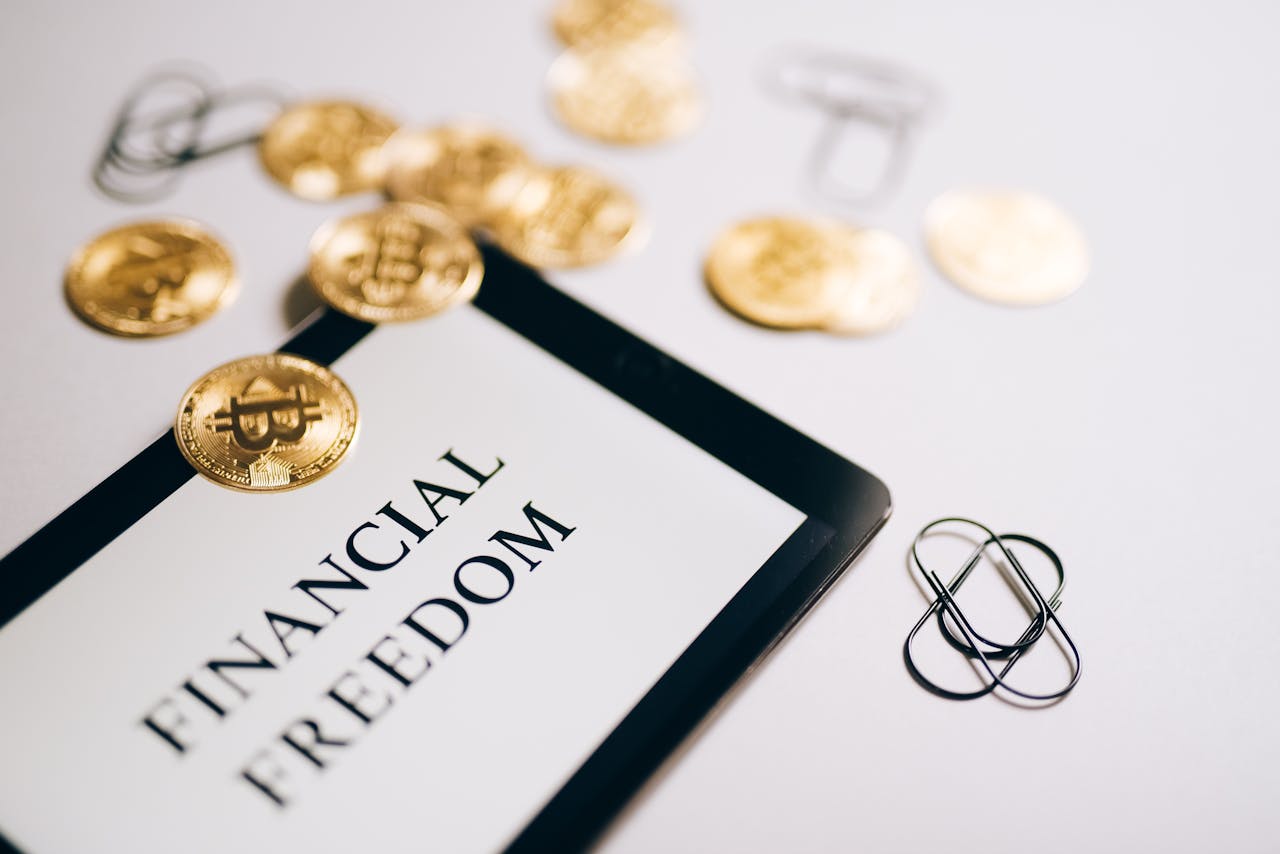 Close-up of Bitcoin coins and an iPad displaying Financial Freedom, symbolizing modern digital savings.